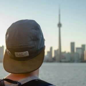 person wearing gray hat facing on city during daytime photography